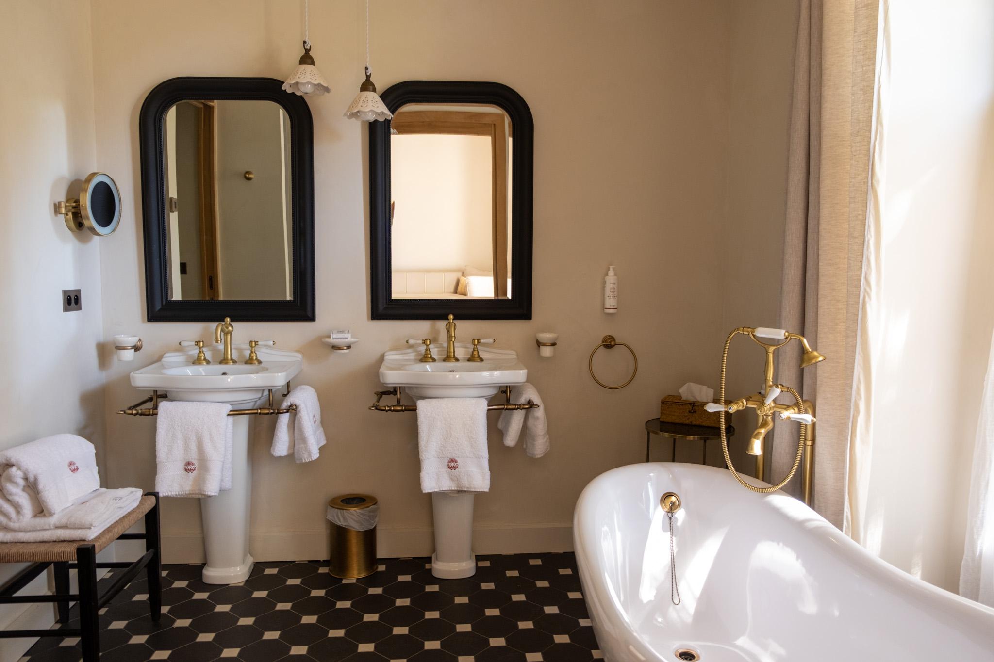 Domaine des Délices d’Ici in Eygalières – bathroom with double sinks, mirrors, and a bathtub